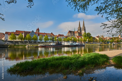 Outlook over the Danube River with the Gothic St Peter's Cathedral from the Marc​-Aurel-shore in the Old Town of Regensburg with a blue sky at sunset; Regensburg, Bavaria, Germany photo