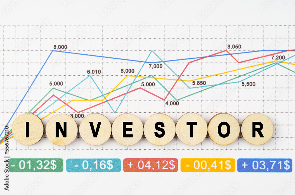 On the financial charts are wooden mugs with the inscription - INVESTOR On the financial charts are wooden mugs with the inscription - INVESTOR