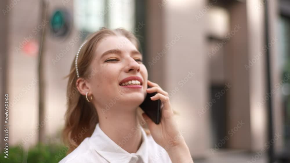 Close-up face of cheerful young woman talking on mobile phone with friends rejoicing smiling white teeth standing on city street in summer day. Pretty female student making online order on smartphone. Close-up face of cheerful young woman talking on mobile phone with friends rejoicing smiling white teeth standing on city street in summer day. Pretty female student making online order on smartphone.