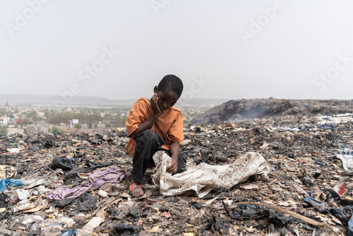 Obraz na plátně Miserable hungry African slum child looking for edible and recyclable items in a
