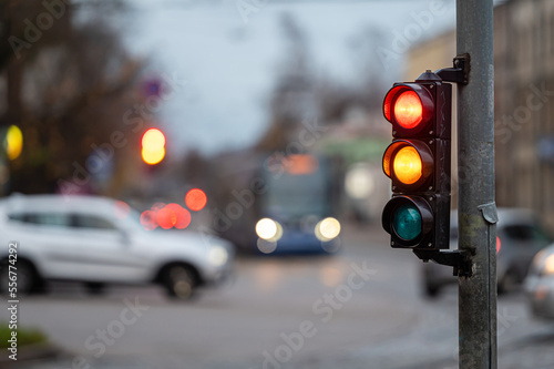 view of city traffic with traffic lights, in the foreground a semaphore with a red and orange light