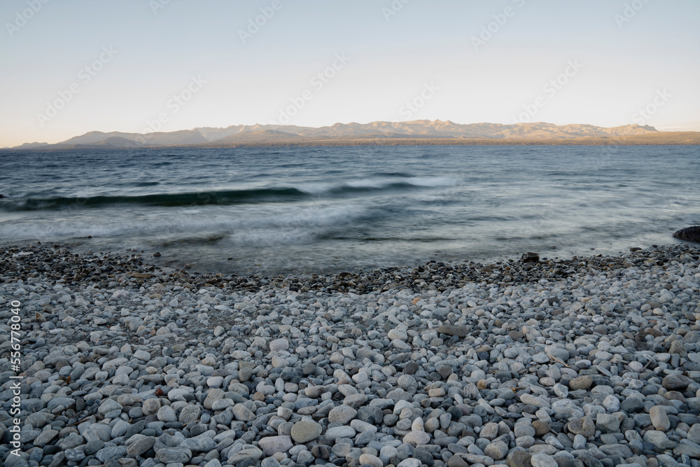 Long exposure shot of Nahuel Huapi lake at sunset. Beautiful blurred water effect, the rocky shore and dusk colors. Long exposure shot of Nahuel Huapi lake at sunset. Beautiful blurred water effect, the rocky shore and dusk colors.