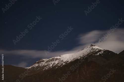 Cielo nocturno sobre una gran montaña nevada en medio del bosque. Fotografía nocturna de las estrellas photo