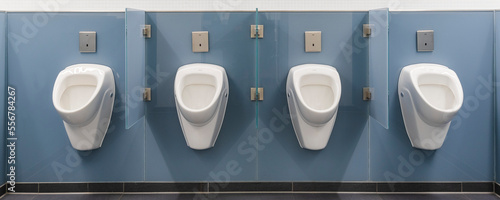 Four white urinals in a row on a blue wall in a men's restroom at the Munich Airport; Munich, Germany photo