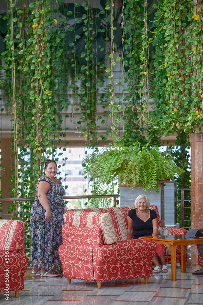 Women are posing in the hall with many hanging plants.