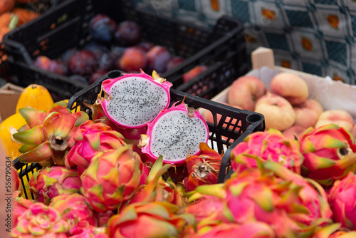 Plano detalle de fruta del dragón o pitahaya partida por la mitad y entera en una caja en un mercado callejero con frutas tropicales en Costa Teguise, Lanzarote Islas Canarias.