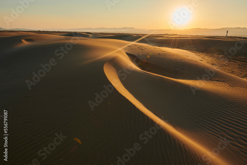 Rippled sand dunes in the evening light at sunset, with a lighthouse in the distance, Ebro River Delta; Catalonia, Spain photo