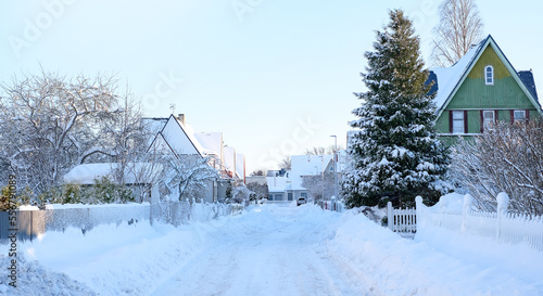 Winter fairy-tale landscape on the street with houses with a triangular roof and roads covered with a lot of snow © Viktoriia