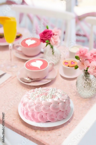 Beautiful scene with coffee cups, pink roses, orange juice and pink cake