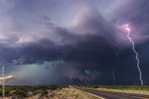 A barrage of lightning strikes the ground as a brief but large cone tornado crosses the highway near Hagerman, New Mexico; Hagerman, New Mexico, United States of America photo