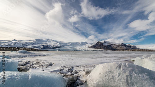 laguna del Fjallsárlón illuminata dal sole, la lingua del ghiacciaio termina direttamente nella laguna scendendo dal versante della montagna