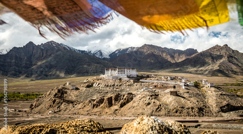 Overview of the Tibetan Buddhist Stakna Gompa on a rocky outcrop in the foothills of the Himalayas, the Leh District, with colorful prayer flags flying above; Jammu and Kashmir, India photo
