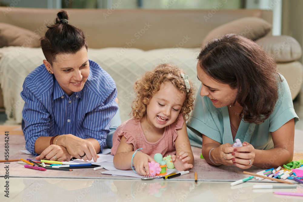 Happy mothers and little daughter playing with toys and drawing pictures together at home Happy mothers and little daughter playing with toys and drawing pictures together at home