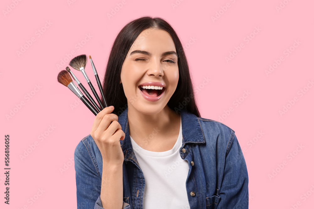 Happy woman with different makeup brushes on pink background Happy woman with different makeup brushes on pink background
