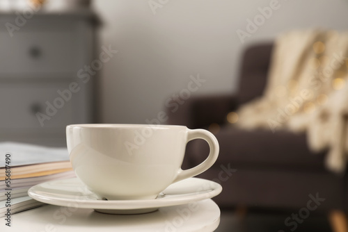 Cup with drink and stack of magazines on white table in living room, space for text