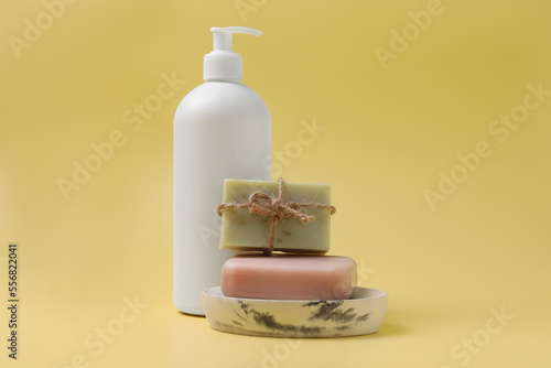 Soap bars and bottle dispenser on yellow background