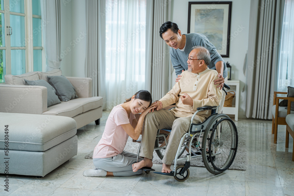 Senior man relaxing sitting on wheelchair in the living room at home,Cheerful family talking to old disabled father,Senior healthcare concept. Senior man relaxing sitting on wheelchair in the living room at home,Cheerful family talking to old disabled father,Senior healthcare concept.