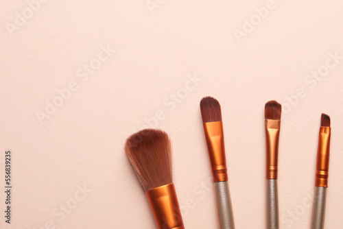 Set of makeup brushes on beige background, flat lay. Space for text