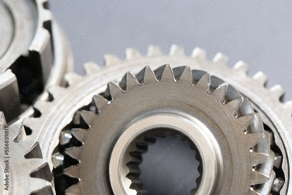 Many different stainless steel gears on grey background, closeup