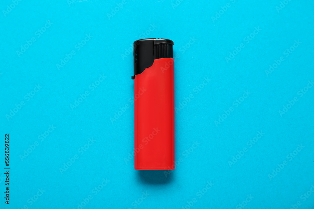 Red plastic cigarette lighter on light blue background, top view Red plastic cigarette lighter on light blue background, top view