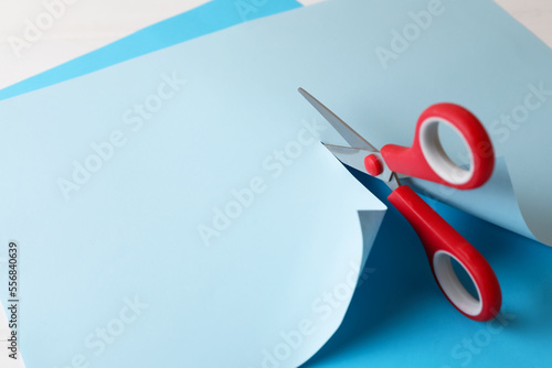 Konstfotografi Red scissors cutting light blue paper on white background, closeup