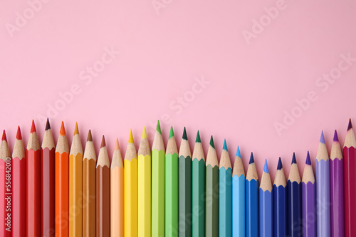 Colorful wooden pencils on pink background, flat lay. Space for text