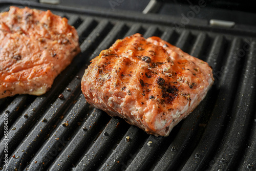 Tasty salmon cooking on electric grill, closeup