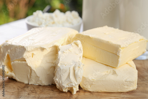 Tasty homemade butter and dairy products on wooden board outdoors, closeup