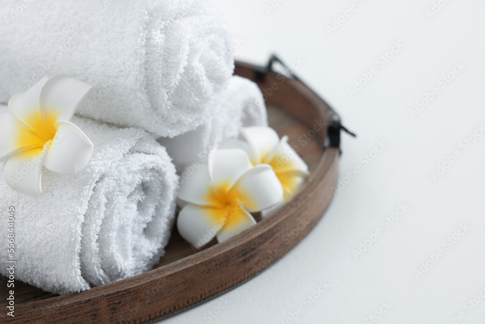 Tray with rolled bath towels on white table, closeup. Space for text Tray with rolled bath towels on white table, closeup. Space for text