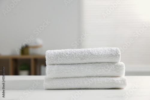 Stacked bath towels on white table indoors