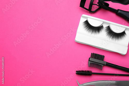 Flat lay composition with fake eyelashes, brushes and tools on pink background. Space for text