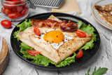 Delicious crepe with egg served on light gray textured table, closeup. Breton galette