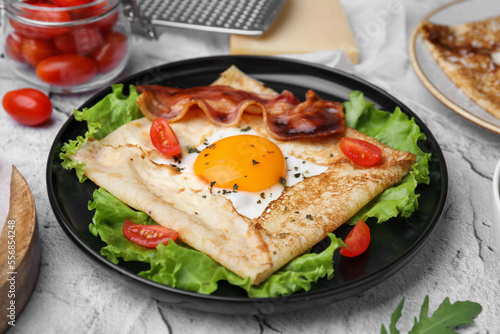 Photos Delicious crepe with egg served on light gray textured table, closeup