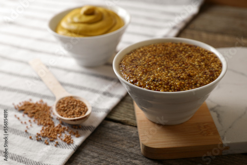 Bowl of whole grain mustard on wooden table, closeup. Space for text