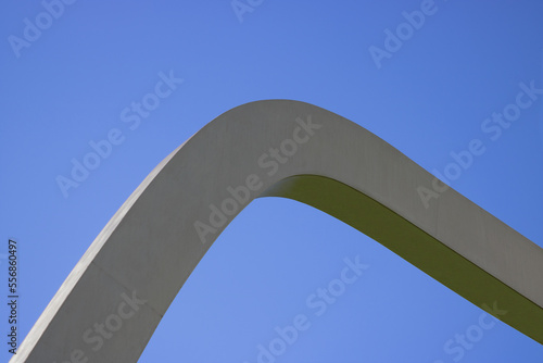 Modern curved metal sculpture against blue sky background outdoor natural daylight.