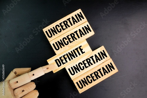 definite and indefinite words. the wooden hand chooses the sure word. concept of certainty. choose certainty photo
