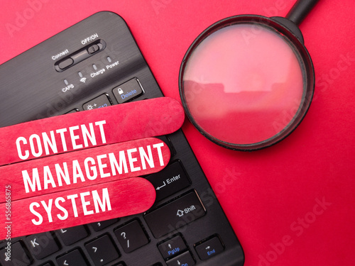 Magnifying glass with the word CONTENT MANAGEMENT SYSTEM on red background.