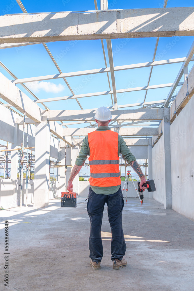 Fototapeta premium Male engineer wearing safety suit and hard hat holding toolbox and electric drill in construction site for building site survey in civil engineering project.