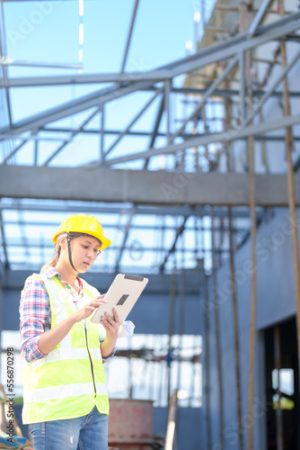 Asia Female civil engineer with inspecting construction plans at building site of high-riser building site survey in civil engineering project.