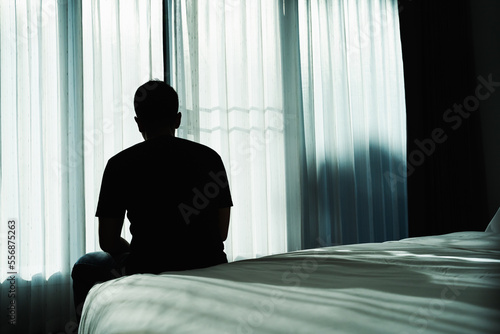 Fotografie, Obraz Silhouette depressed man sadly sitting on the bed in the bedroom