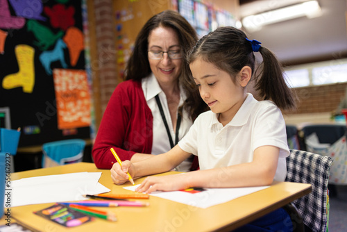 Female Teacher Helping Young Schoolgirl Draw photo