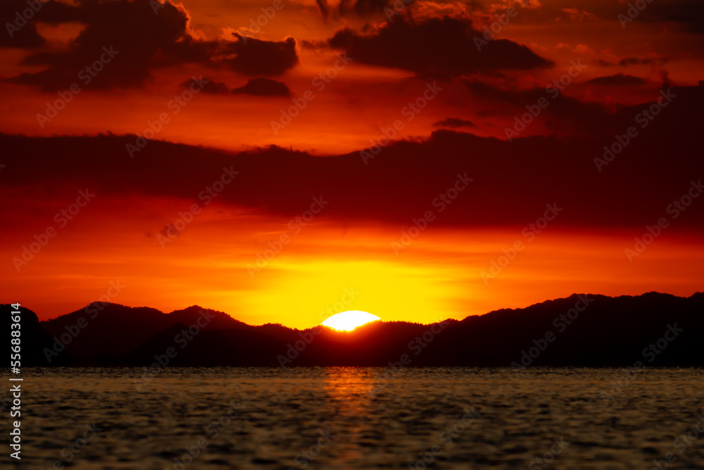 Sunset with dark cloud and silhouette mountain at the lake in golden time.
