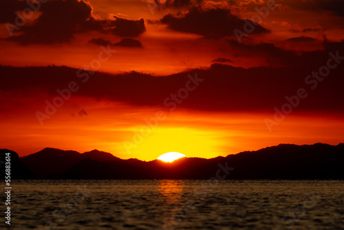 Sunset with dark cloud and silhouette mountain at the lake in golden time.