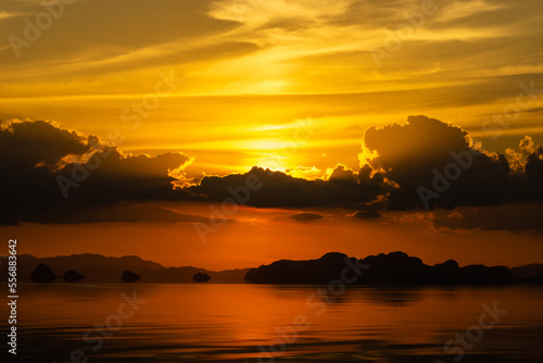 Sunset sky with dark cloud and silhouette mountain mirror on the water at the lake in golden time.