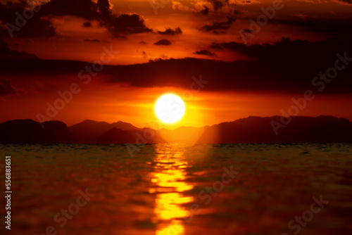 Sunset sky with dark cloud and silhouette mountain at the lake in golden time.