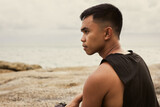 Serious profile portrait of Filipino man by the sea. Pensive male person alone with contemplation look outdoors. Inner peace concept