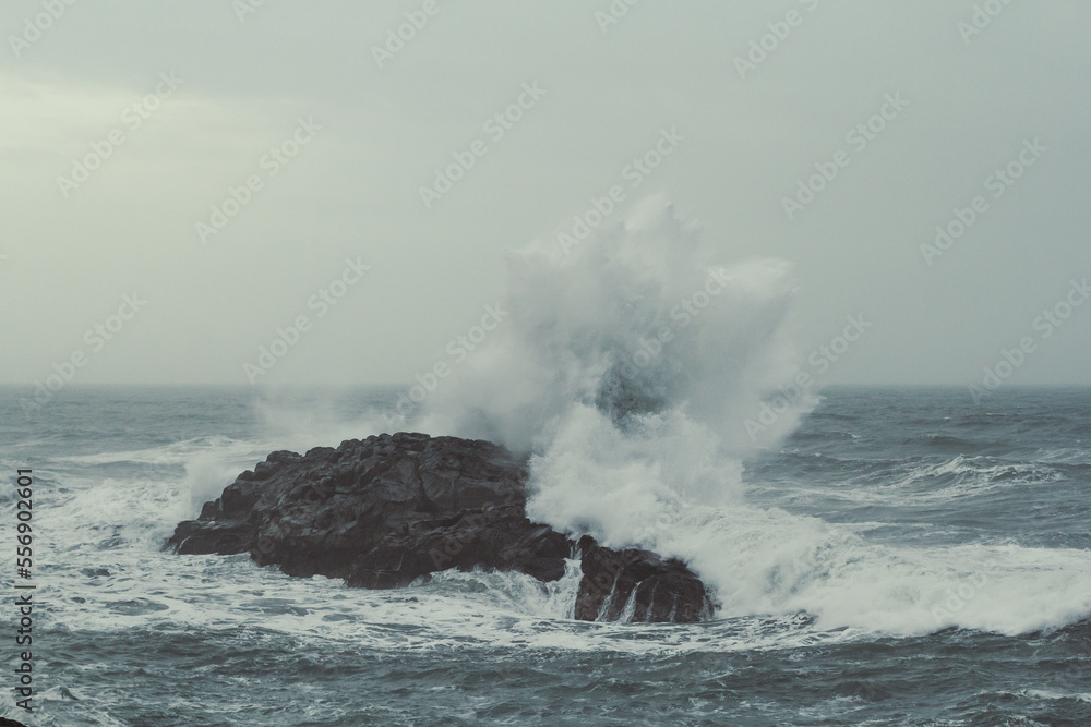 Water splash over cliff in sea landscape photo. Beautiful nature scenery photography with grey sky on background. Idyllic scene. High quality picture for wallpaper, travel blog, magazine, article Water splash over cliff in sea landscape photo. Beautiful nature scenery photography with grey sky on background. Idyllic scene. High quality picture for wallpaper, travel blog, magazine, article