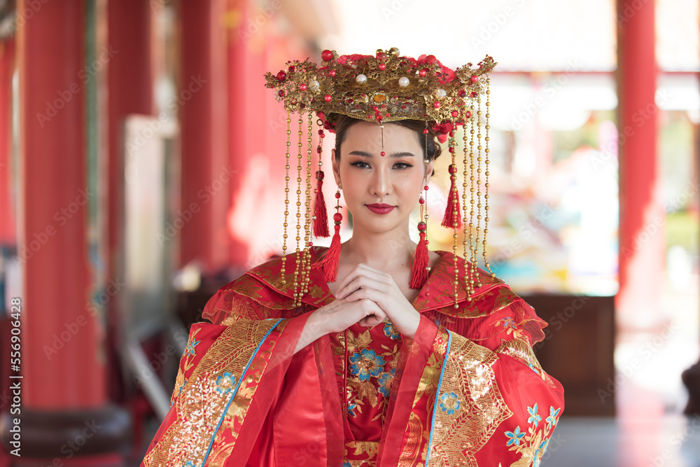 portrait of a woman. person in traditional costume. woman in traditional costume. Beautiful young woman in a bright red dress and a crown of Chinese Queen posing against the ancient door.