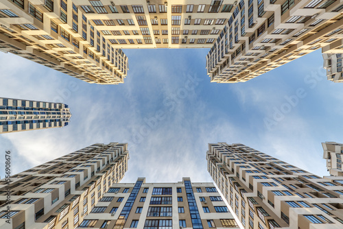 Schilderij op canvas view up from ground to blue sky among skyscrapers, look at house from bottom up