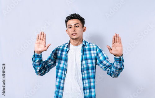 Scared and horrified man with raised palms, Man with a frightened face with his hands raised in front. Portrait of scared person with raised hands, Scared guy with raised hands in front photo